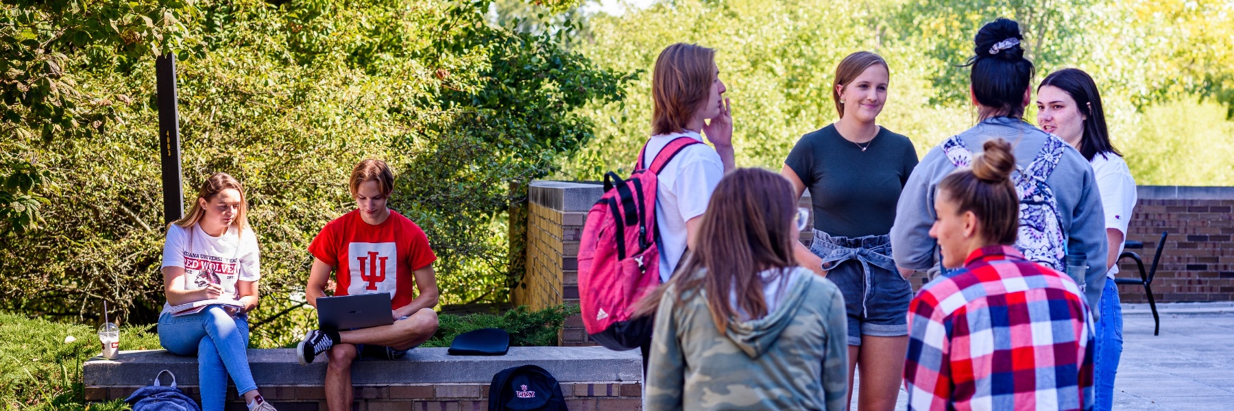 A group of students chatting outside on a sunny day.