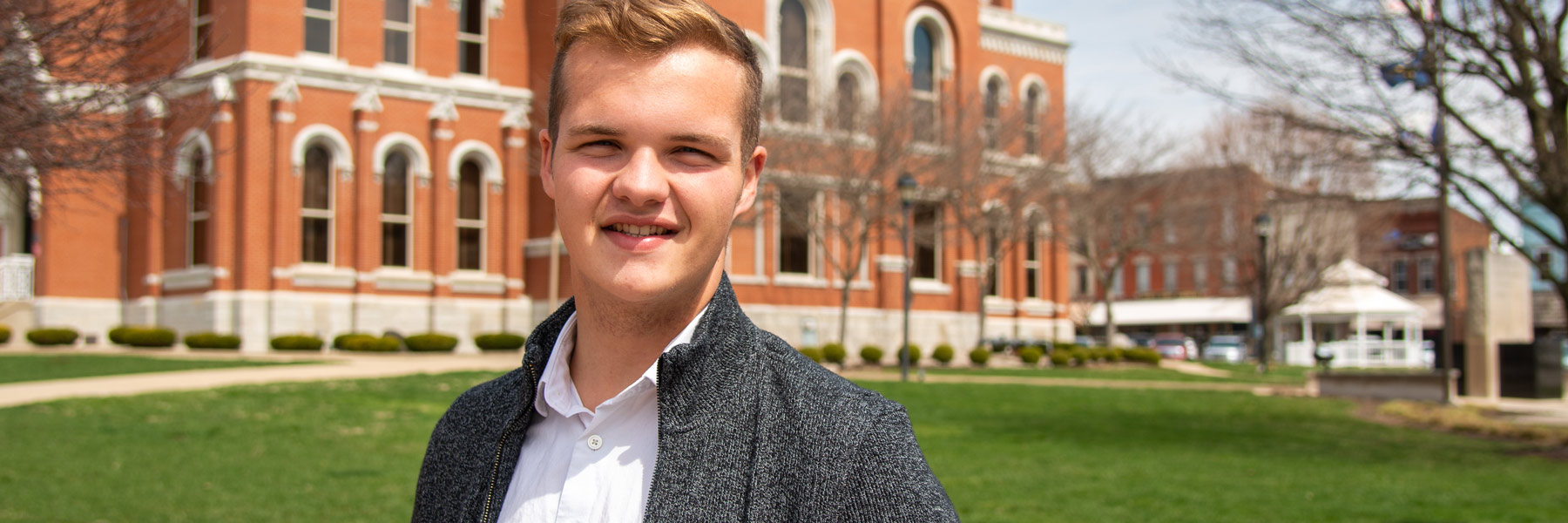 Alex standing and smiling in front of the Decatur County courthouse.